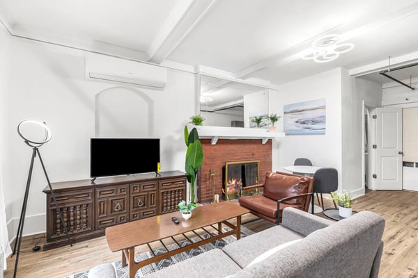 Modern living room with fireplace, gray and cognac leather seating, wooden media console, and white shiplap walls
